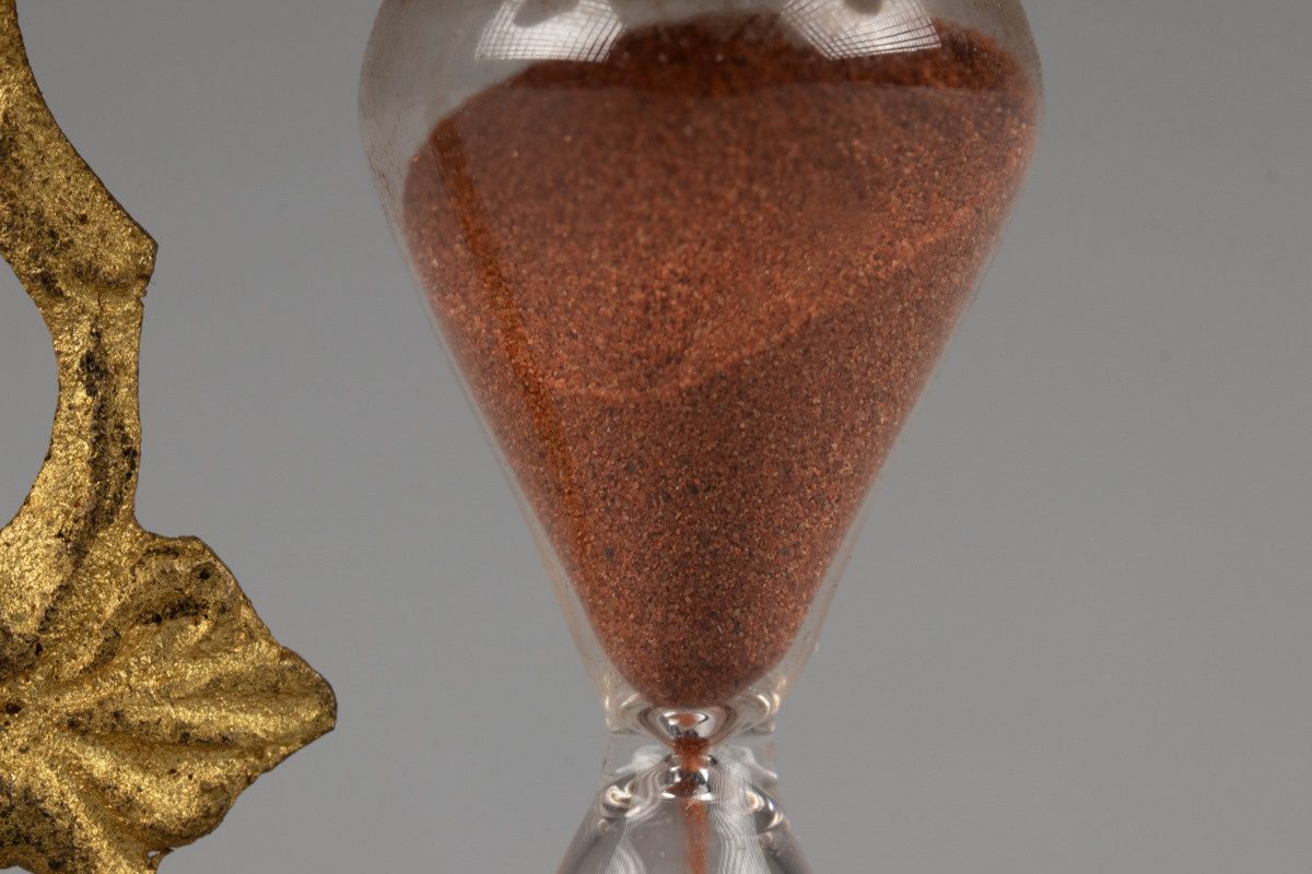 Timeglass med stativ av gullforgylt metall. Tiden det tar for at sanden skal renne fra den ene kolben til den andre er ca 2,32 min.