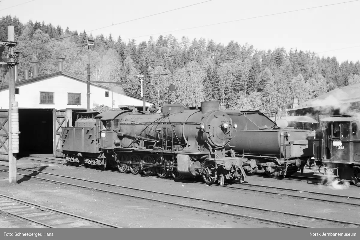 Damplokomotiver foran lokomotivstallen på Hønefoss stasjon. Til venstre type 39a nr. 308, til høyre 25a nr. 292. Bak skimtes type 63a