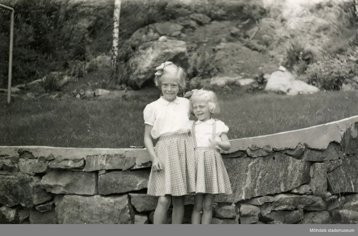 Första examensdagen för Eva i juni 1952. Systrarna Eva (gift Kempe) Pettersson och Karin (gift Hansson) står framför stenmuren på Gamlehagsvägen i Torrekulla.