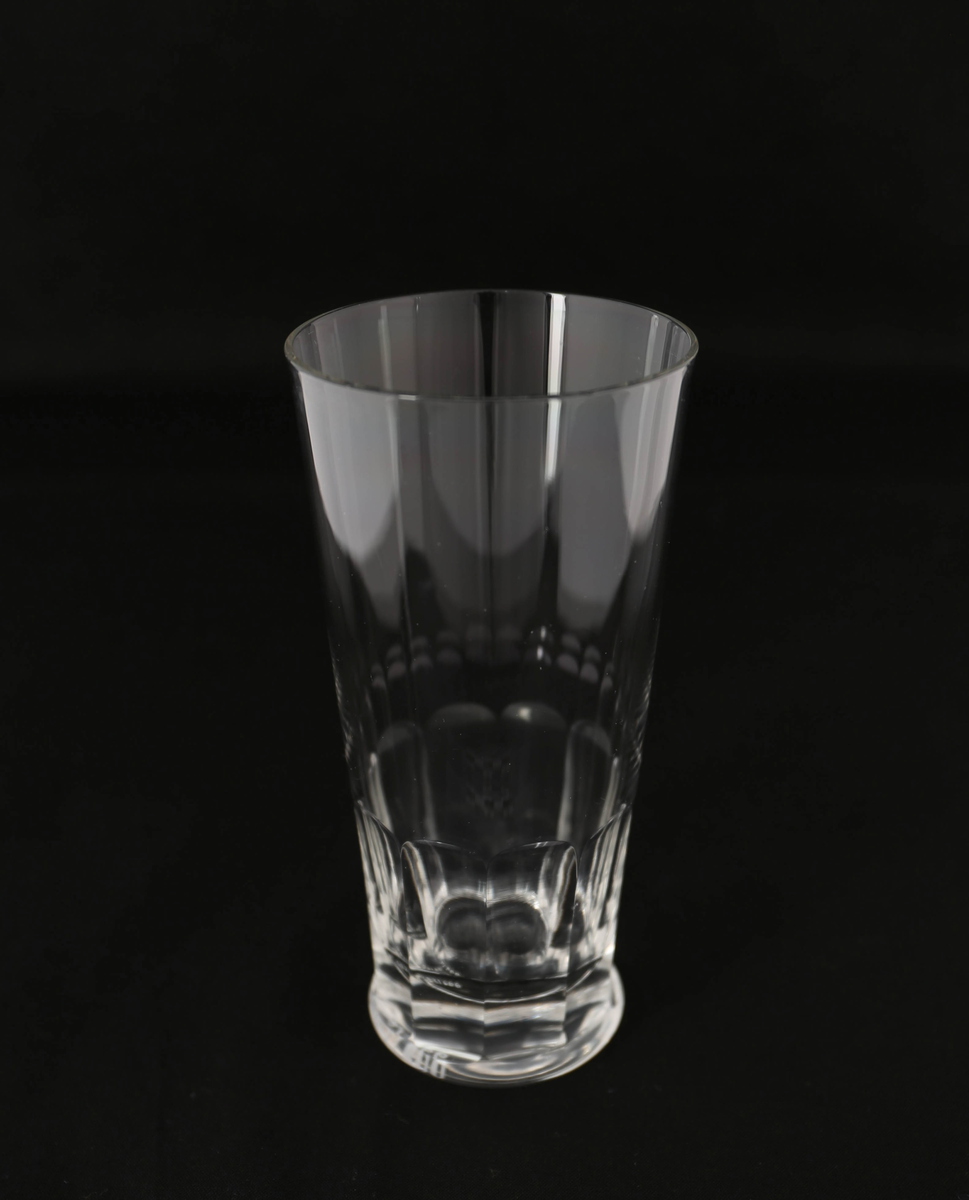 Blåst ølglass av glass med høy, konisk form og fasettslipt dekor nederst ved rund, flat fot.