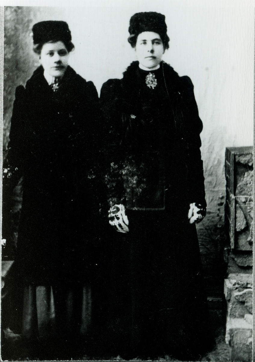 Portrett, av 2 damer med fingervanter,jakke,lue,kjole og sølje.