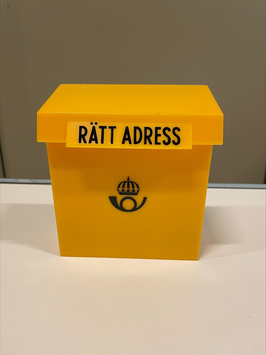 Adressregister. En låda i gul plast med postens logotyp på framsidan. På locket texten "RÄTT ADRESS". I lådan blanka kort för att skiva adresser på och ett alfabetiskt flikregister i ljusblå kartong. 

Adressregistret är oanvänt.