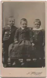 Portrett av tre barn, to gutter i rutet og stripet jakke, me