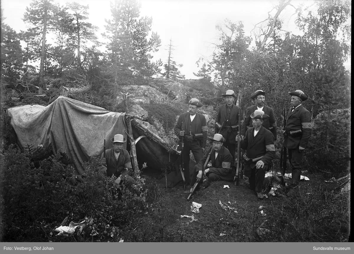 Hemvärnsövning i Juniskär, män med landsstormsuniformer och vapen står invid ett tält.