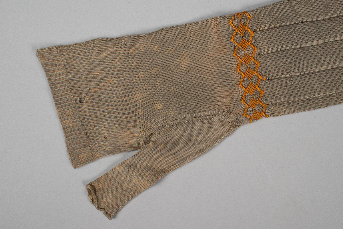 Et par lange, fingerløse hansker i glattstrikket silke med geometrisk silkebroderi rundt håndleddet