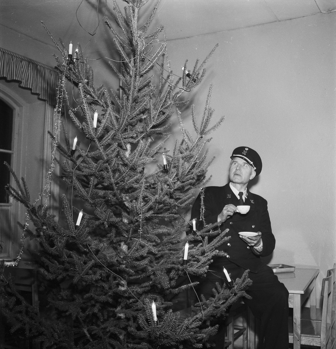 Man i uniform dricker kaffe vid julgran, Uppsala julen 1951
