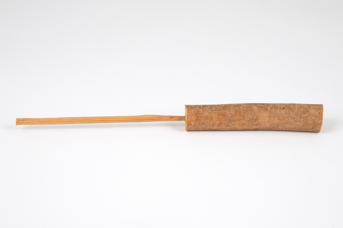 Tredukke laget av en trepinne med bark montert på en tynn pinne. Ansikt av ubehandlet tre, malt med svart. Dukken forestiller en mann og hører sammen med NK1991-039-003 (kvinne).