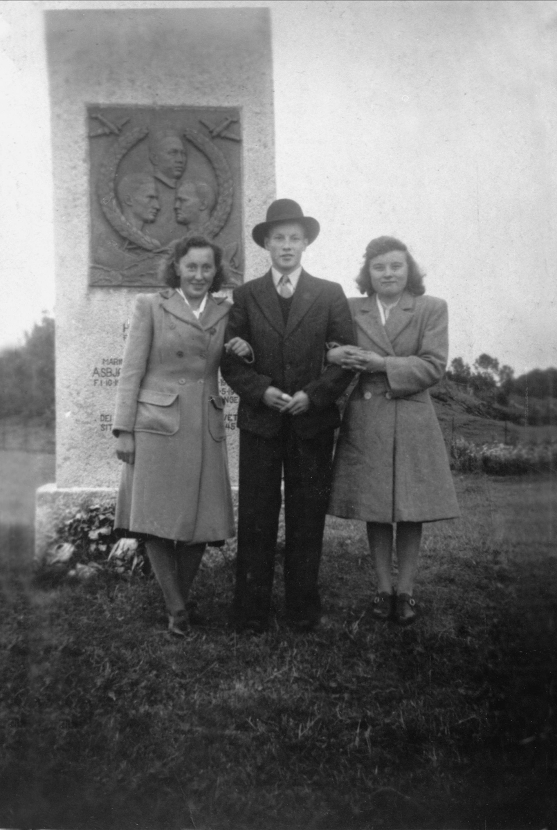 To kvinner og en mann foran bautaen til minne om falne fra Skånland under andre verdenskrig.