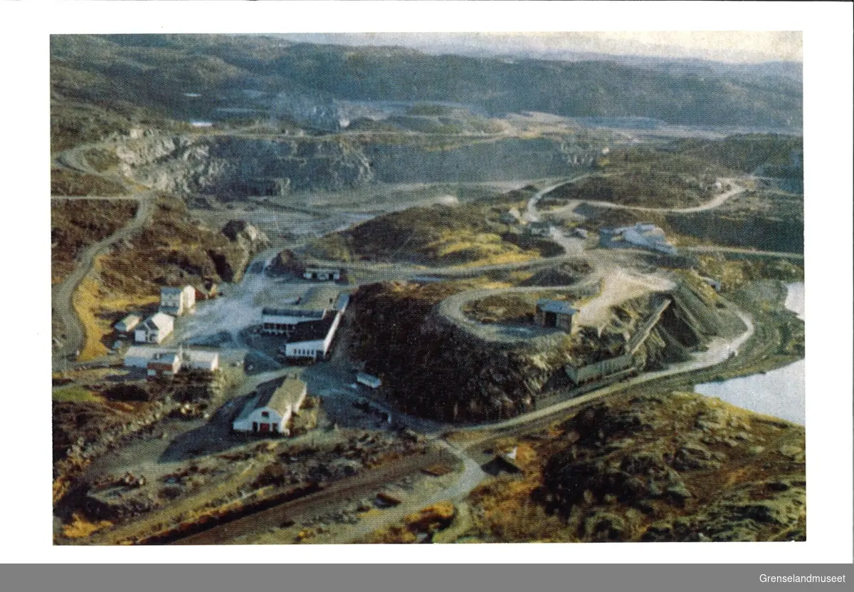 Avfotografert i luftperspektiv er gruveselskapet A/S Sydvaranger sitt industrianlegg i Bjørnevatn. På bildet kan man se kontorbygning, velferdshus og mekanisk verksted. I bakgrunnen kan man se Vestmalmens dagbrudd.  