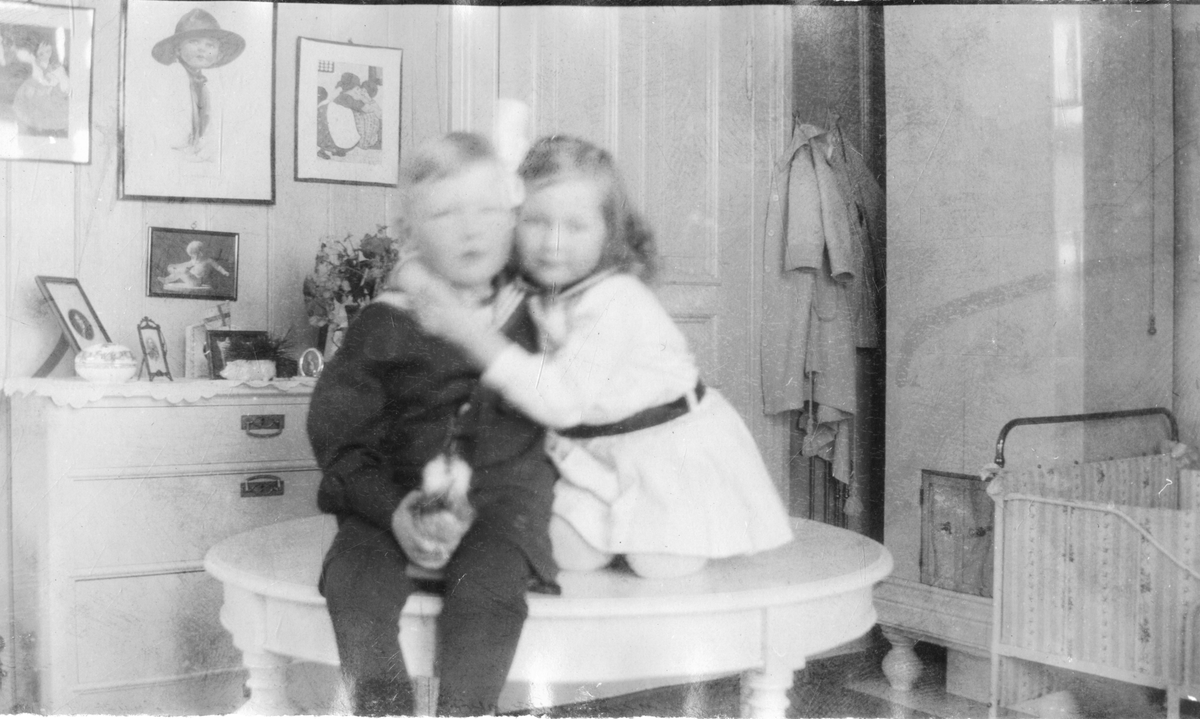 Foto av to barn som klemmer mens de sitter på et bord, er muligens søsknene Niels Frederik Aall og Cecilie Aall