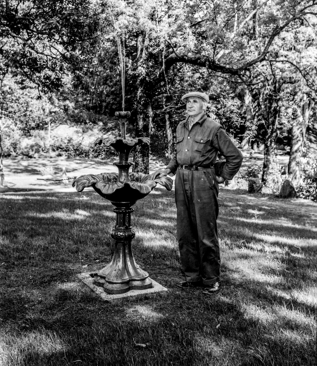 Tor Kivle står ved siden av fontenen. . 18.06.1955