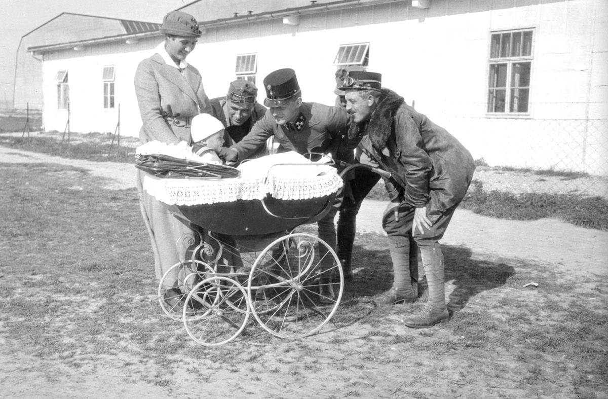 Fyra militärer från Österrike-Ungern hälsar på pojke i barnvagn. En kvinns står bredvid.
Omkring 1914-15.