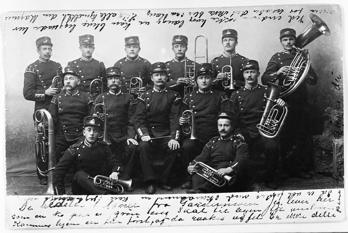 Militært musikkorps året 1905. To personer er identifisert: Stående til venstre Magnus Øfstaas, sittende til høyre Nils Evenrud.