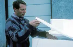 Mann pakker fisk i isoporkasser med is.