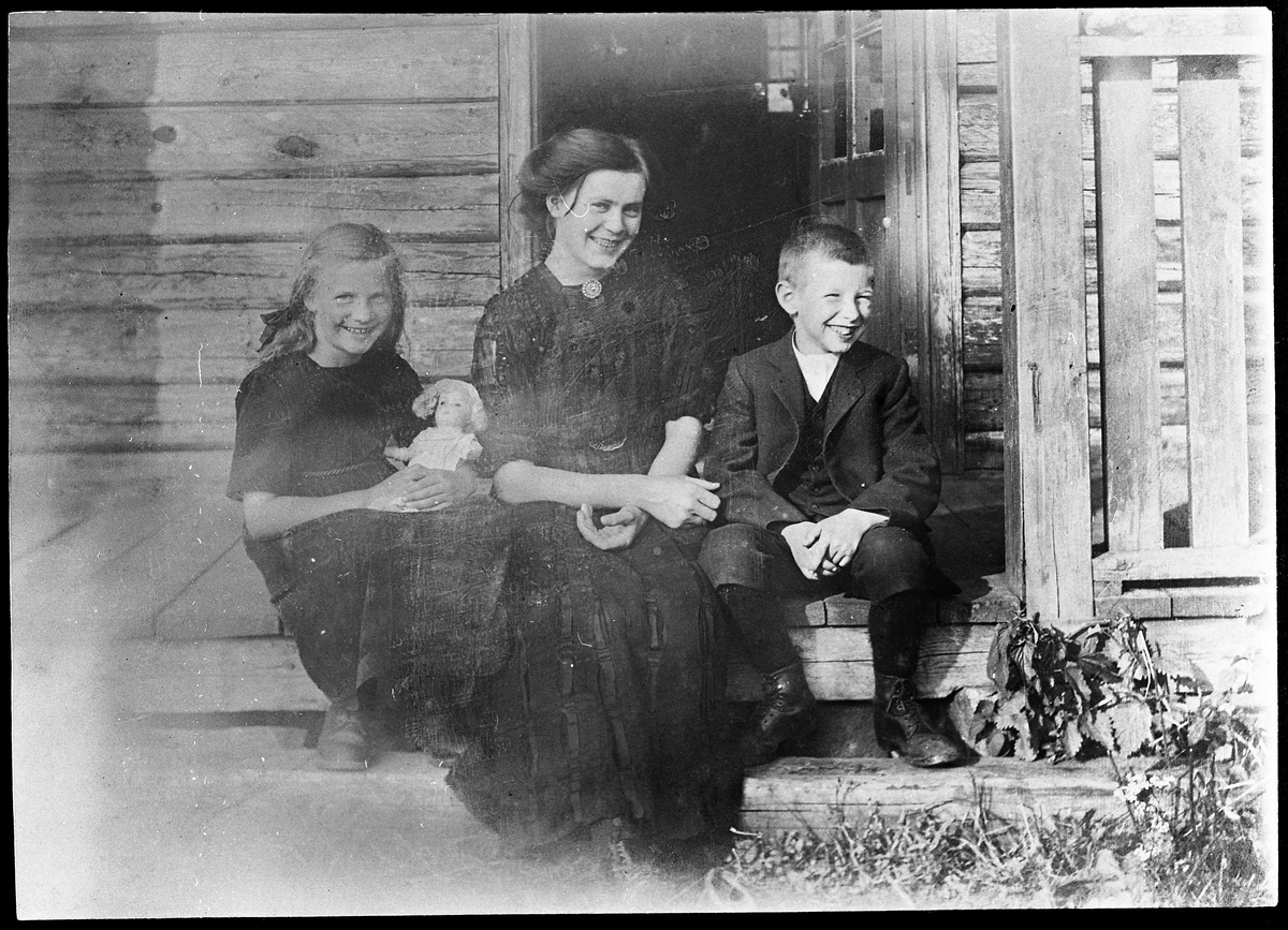 Kvinne og to barn på trappa trolig foran Ramstadstørhuset i Amundalen på Totenåsen. Året er 1915. Personene er kanskje familien til fotografen som muligens var kontorsjefen på melkefabrikken på Kapp, men dette er bare en antakelse fra informantens side.