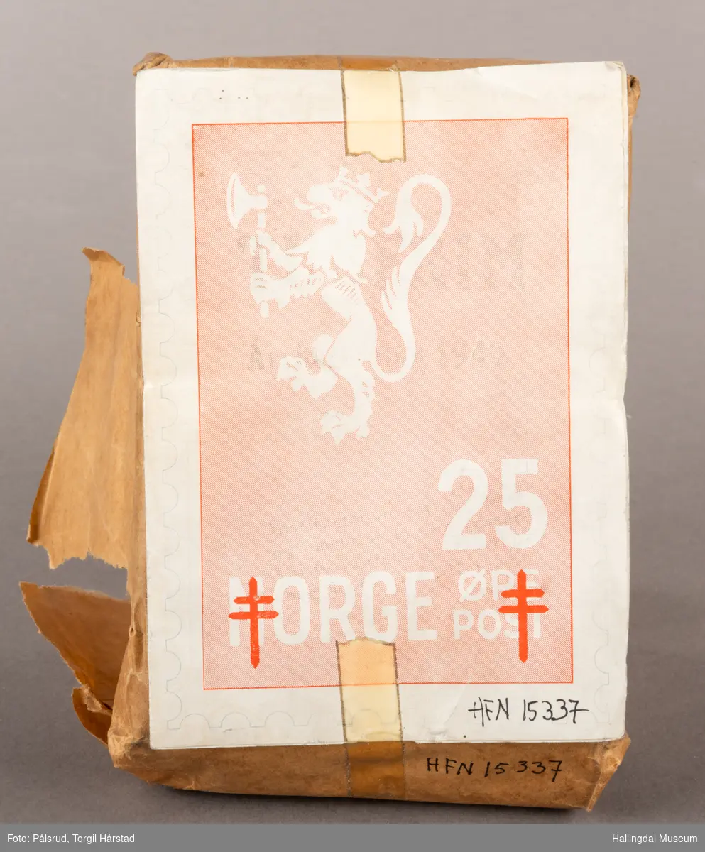 En pakke med uåpne trykksaker til Tubfrim, blant annet årsberetningen for 1949. Pakken er pakket inn med kraftpapir med illustrasjonen til forsiden til årsberetningen utenpå: Et frimerkemotiv med en hvit riksløve på lyserød bakgrunn, under står det Norge og 25 øre post. I tillegg er det plassert to røde Lothringenkors, eller dobbeltkors, i de nederste hjørnene.