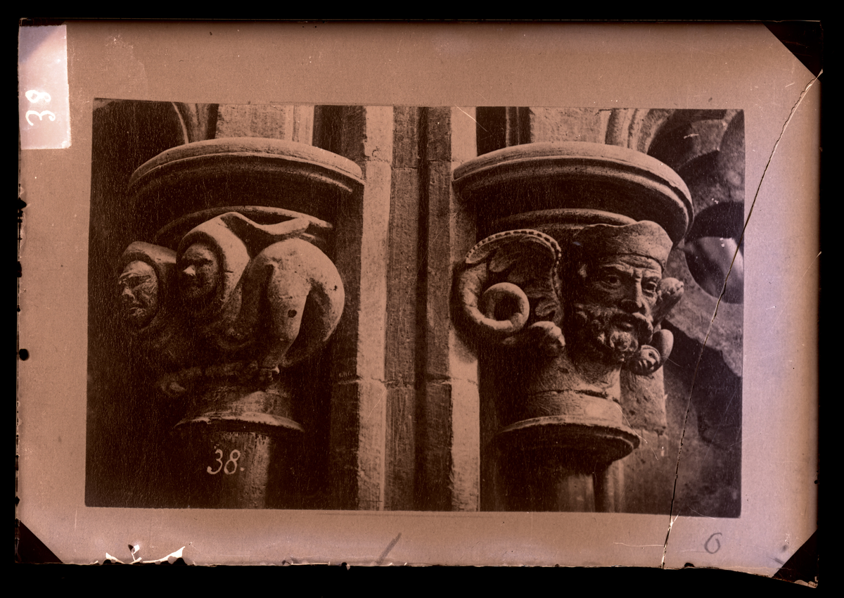 Skulpturer på kapiteler i ambulatoriet i oktogonen i Nidarosdomen. To munker til venstre og et bevinget hode til høyre (fabeldyr). Ifølge Hovedkatalog for fotografier er bildet tatt etter restaurering.