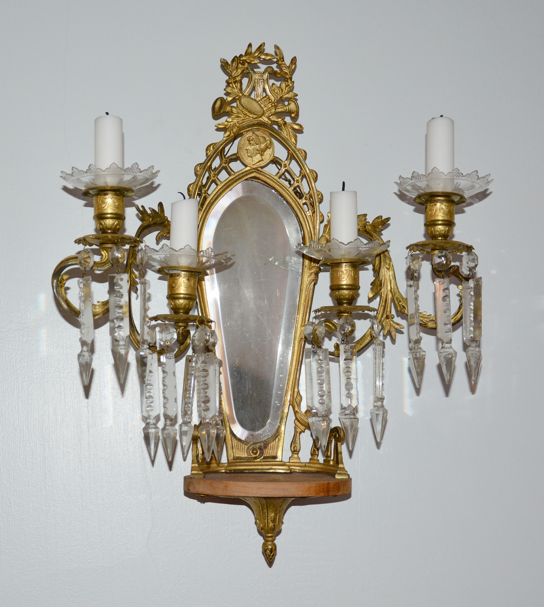 Lampett med fire armer, prismer, dryppskåler i glass, speil og lite konsoll.