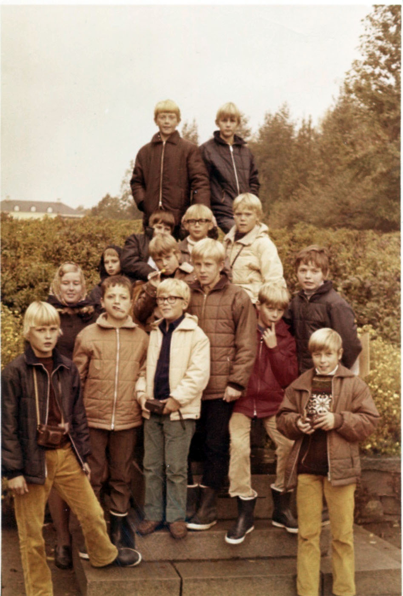 En skolklass från Brattåsskolan befinner sig på lägerskola/skolresa till Ransberg i Värmland, 1980-tal. De står uppställda på en liten kulle. I bakgrunden skymtar Ransbergs Herrgårdstak.