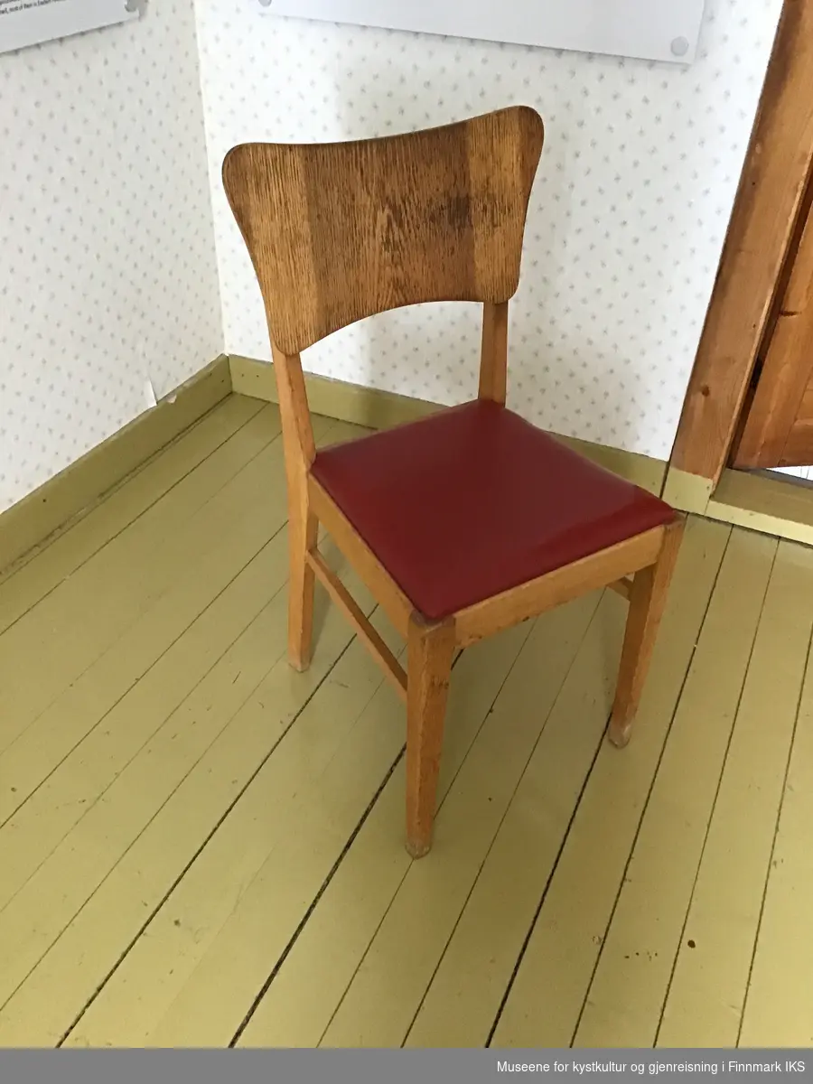 Fire spisestuestoler av tre med polstrete seter som er trukket med rød kunstskinn. Rygglenene er av finérplater som har svungne kanter.