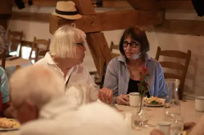 To damer sitter ved bordet og snakker sammen.