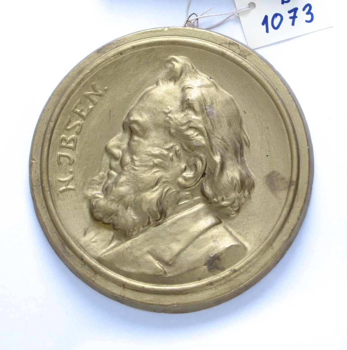 Sirkulær medaljong med   profilportrett, venstrevendt,  tekst langs venstre kant: