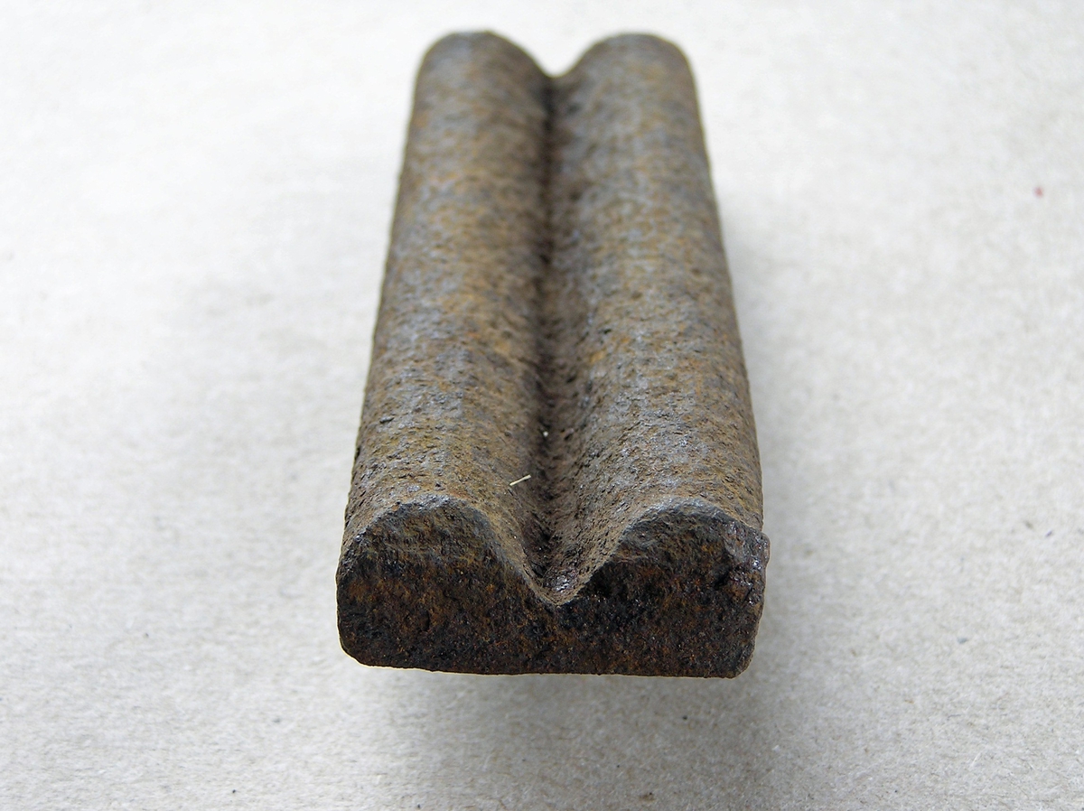 Smidd jernstykke til bruk ved smiing av merkeøks. Merket ble formet rundt stempelet. Uten håndtak - antagelig holdt med tang. Noe rust.