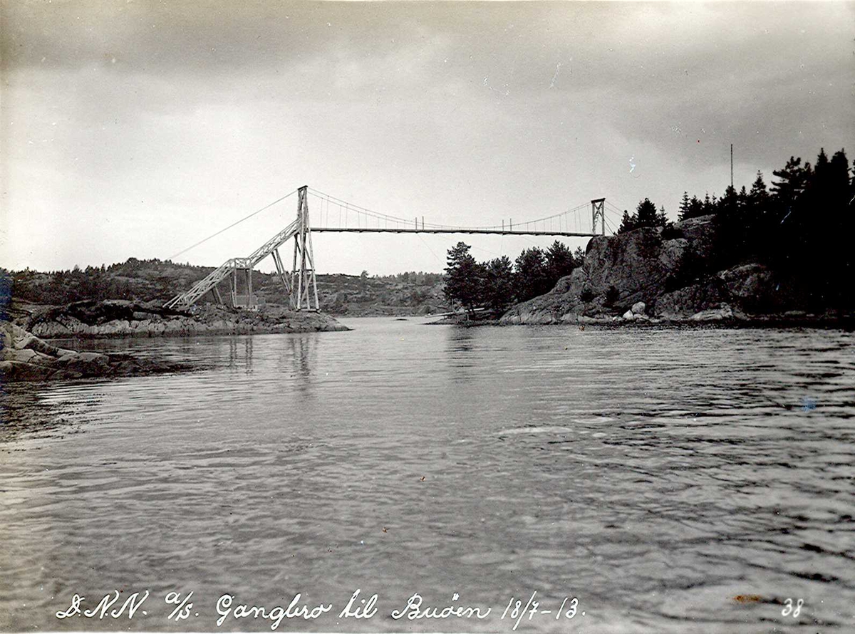 "18/07-1913" Nitriden. Gangbru fra Langnes (Pinnen) til Buøy. Kun tillatt adgang for dem som bodde på Buøy. Brua var så høy at marinens båter kunne passere under. Trekonstruksjon.