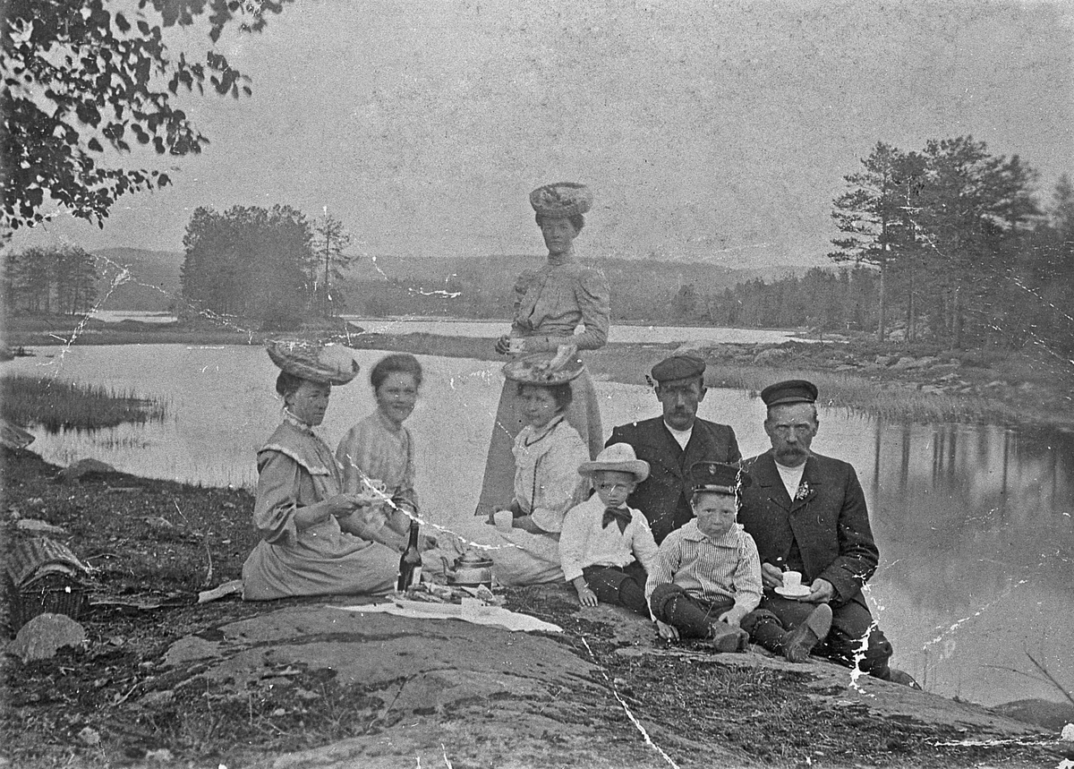 Utflukt ved innsjø. Ca. 1905. 
Kvinnen som står er Marie Halvorsen. Mannen som sitter ved siden av henne er Olav Halvorsen. De andre er ukjent.