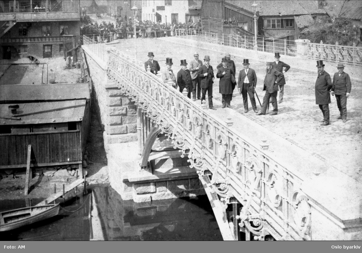 Hatteprydete menn på Hausmanns bro, ved åpningen 30. juni 1892. Folkemengde som venter bak sperringene. Stadsingeniøren - Fotografier af Kristiania (albumtittel). Akerselva.