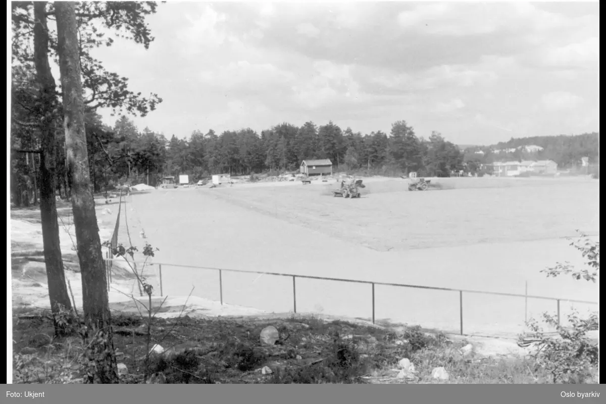 Idrettsparken sett mot nord mot bebyggelse i Vetlandsveien. Såing / bearbeidelse av fotballfeltet fra traktorer. Trasopbanen