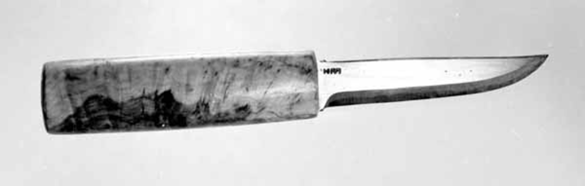 Kniven er en brukskniv med skaft av valbjørk. Den er ubrukt. Bladet svinger svakt oppover mot odden. 
Den er stukket inn i en knivkjuke (SJF 3215).