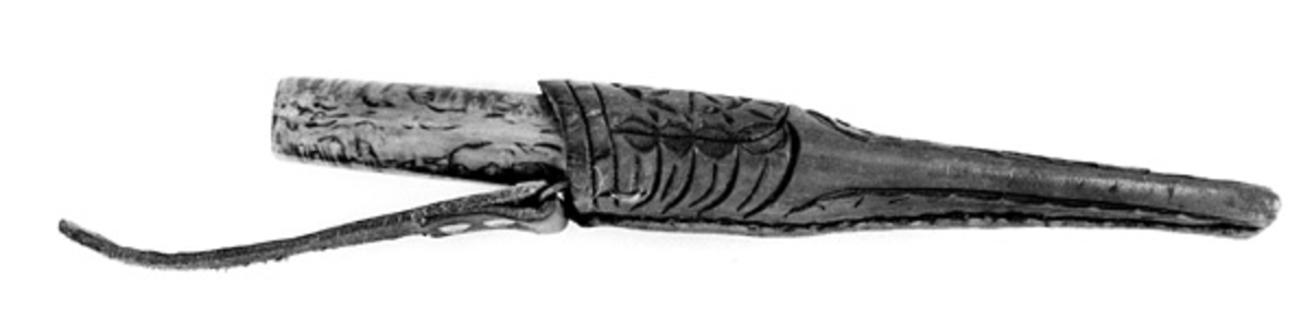 Tollekniv med slire, lagd av Elling Tørnes (1903-1982) fra Drangedal i Telemark. Kniven er 20,3 centimeter lang, målt fra knivspissen til den bakre enden av skaftet. Sjølve bladet er 9,7 centimeter langt. Bredden, målt ved brystningen er 2,0 centimeter. På dette punktet er tjukkelsen på bladet 3,0 millimeter. Det smalner til cirka 2,5 millimeter i den fremre enden. Bladryggen er konvekst buet. Bladet har ikke noe produsentstempel, men det er sannsynligvis masseprodusert. Skaftet er lagd av valbjørkved. Det er rett, noe konvekst i lengderetningen og har et ovalt tverrsnitt. Største tverrsnitt er 1,9 X 2,6 centimeter. Skaftet later til å være innsatt med lysebrun beis og overstrøket med klarlakk.

Slira er sydd av drøyt 3 millimeter tjukt, brunfarget lær. Den er 15,0 centimeter lang. Opphenget er ikke innregnet i dette målet. Formen er symmetrisk om sliras midtakse i lengderetningen. Bredden i den øvre enden er 3,6 centimeter. Sliresømmen er plassert på den sida som vil vende inn mot kroppen når knivstellet bæres i bukselinninga. Den øvre delen av slira, som skal omslutte den fremre enden av knivskaftet, er rundoval. Den nedre delen, som skal skjerme bladet, er mer flattrykt. Slira har innskåret dekor. På forsida av den øvre delen er det skåret en rosett. Også på den nedre delen er det en rosett, men denne er forlenget med en bladflik. Også på baksida av slira er det skåret et blad, her med sliresømmen som en imaginær stengel. Øverst, på baksida av sliremunningen, er det innstykket ei ståltrådhempe, som fungerer som hengslingspunkt for et oppheng. Dette dreier seg om en 10,5 centimeter lang lærstropp med ei vertikal spalte, et knapphull, i den øvre enden. Slira er litt ffor kort for denne kniven. Bladet stikker ut - cirka 5 millimeter - i den nedre slireenden. Dette reiser spørsmål om slira egentlig er lagd til denne kniven.
