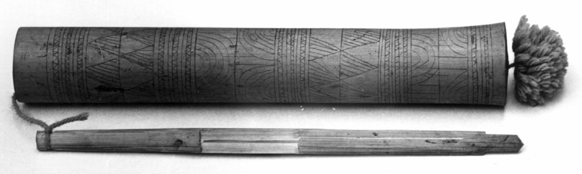 Munnharpe skåret av ett stykke bambus. Snerpen løper helt parallelt med rammen som er rett og smal.
Harpen festet med en lilla bomullsnor til et etui av bambus-rør lukket i den ene enden. Etuiet er beiset lilla og dekorert med innrisset strekdekor.