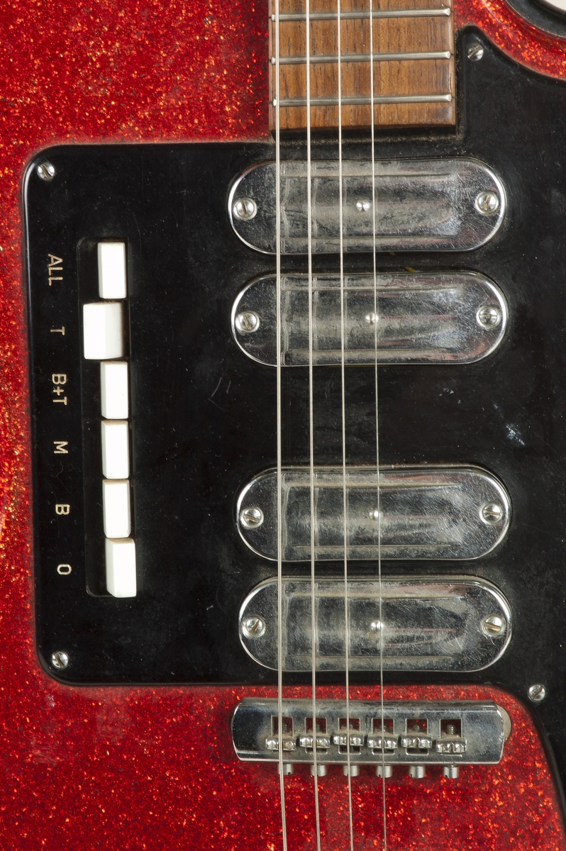 Elektrisk gitar lakkert i "sparkling red" på kroppens overside, blank sort finish på baksiden. Enkel cutaway. Fire pickuper, en volumkontroll og en tonekontroll. Seks hvite brytere/pickupvelgere. Hode og hals i et stykke. Alle stemmeskruene er på samme side. Ovalt lokk på baksiden ved overgangen til halsen.