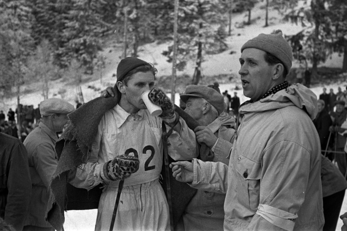 NM. Norgesmesterskap på ski, langrenn på Høsbjør i Furnes 1949. Skisport. Vinteridrett. Ukjent langrennsløper inntar drikke etter målpassering. 