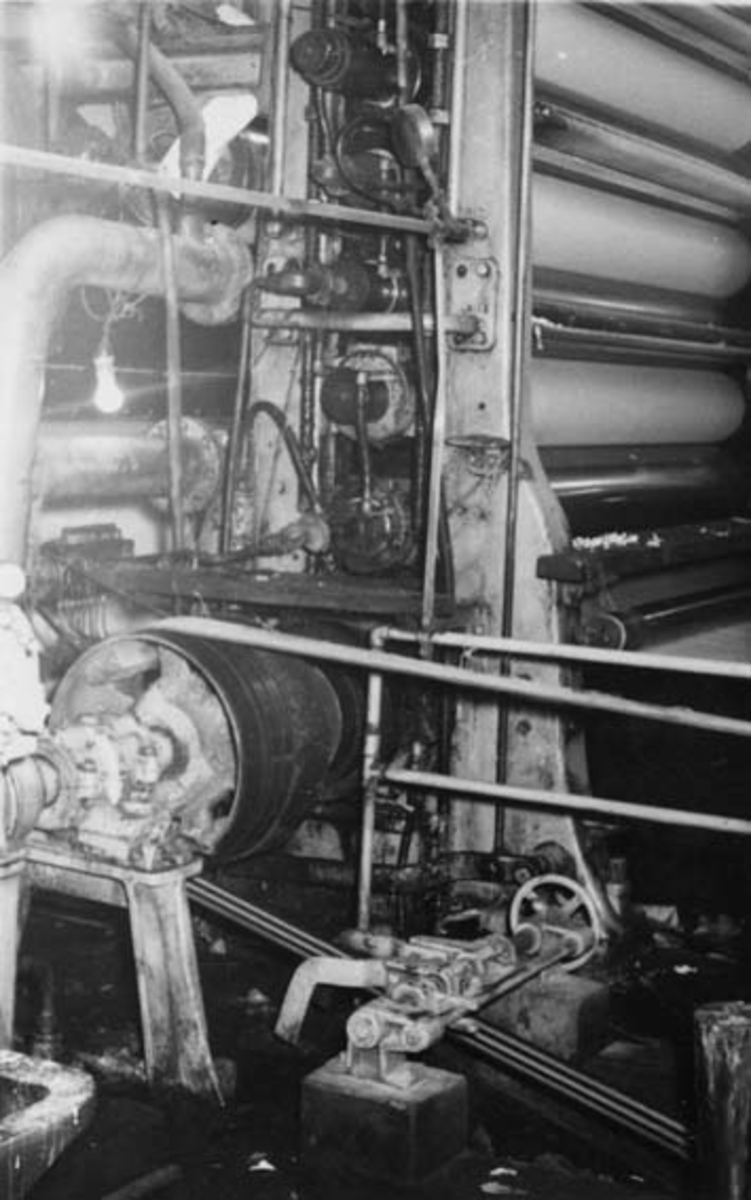 Glitten til PM 3 ved Drammenselvens Papirfabrikker på Modum i Buskerud, slik den så ut i 1955.  Glitten består av en vertikal stabel med stålvalser.  Papiret passerer mellom valsene - ovenfra og nedover - på sin veg fra kjølesylinderen til opprullinga på "tambur".  Glitten hadde to funksjoner: Den skulle glatte ut ujevnheter i papiret og korrigere skjevheter i papirbanen, samtidig som den skulle gi papiret en blank overflate. 
