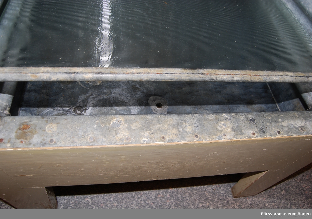 Isskåp av trä med bleckplåtsklädd isbehållare upptill. Smältvattnet rinner längs skåpets sidor ner till behållare i botten med kran för avtappning. Skåpets inredning består av tre glashyllor med lister av metall i framkanten. Insidan är klädd med bleckplåt, där sidorna har vågig form för att möjligge valfri placering av hyllorna. Skåpets dörr är låsbar.