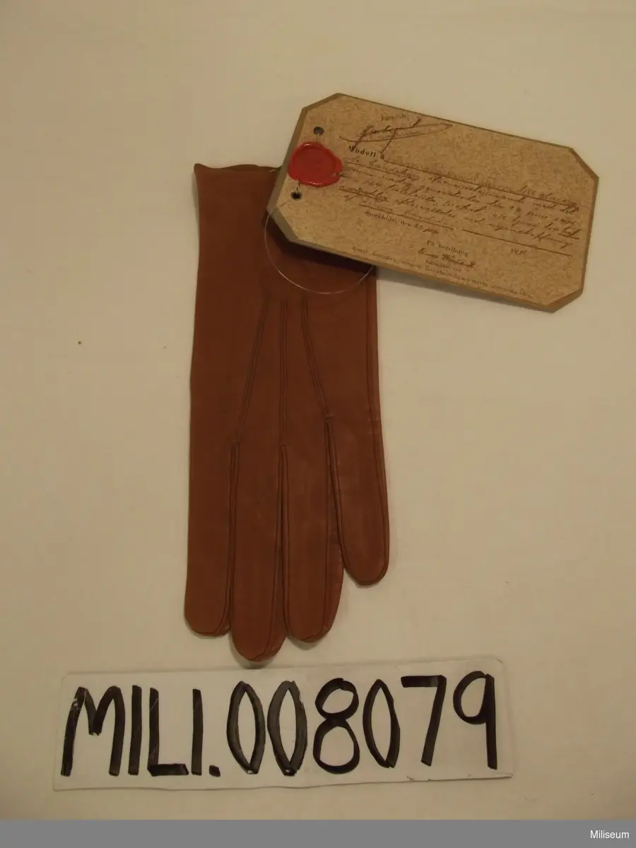 Glaserade handskar m/1911, modellexemplar 

Vidhängande modellapp: " Modell å färg prov å brunt skinn till glaserade handskar...)