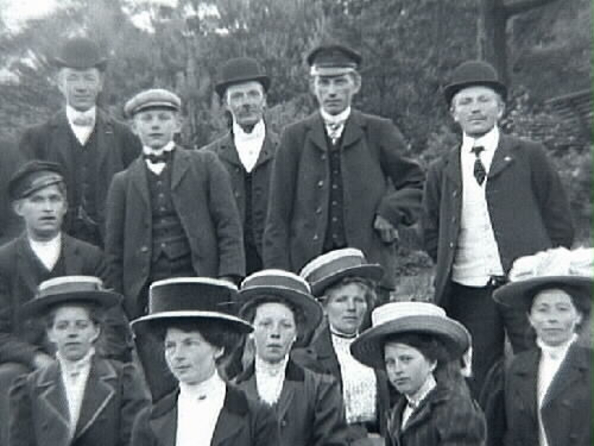 Gruppbild med c:a tjugo personer fotograferade utomhus. Mannen med plommonstop, stående trea fr vänster är Klas Johansson i Stenshult, född 1888.