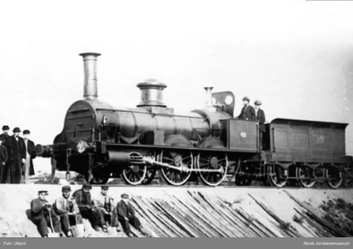 Hovedbanens damplokomotiv nr. 5 med lokomotivpersonale og banearbeidere sittende ved siden av skinnegangen