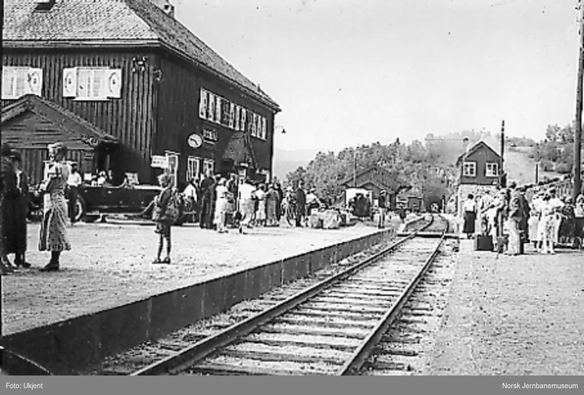 Dombås stasjon sett fra plattformen og mot tunnelen, reisende på plattformen, tog i spor 2