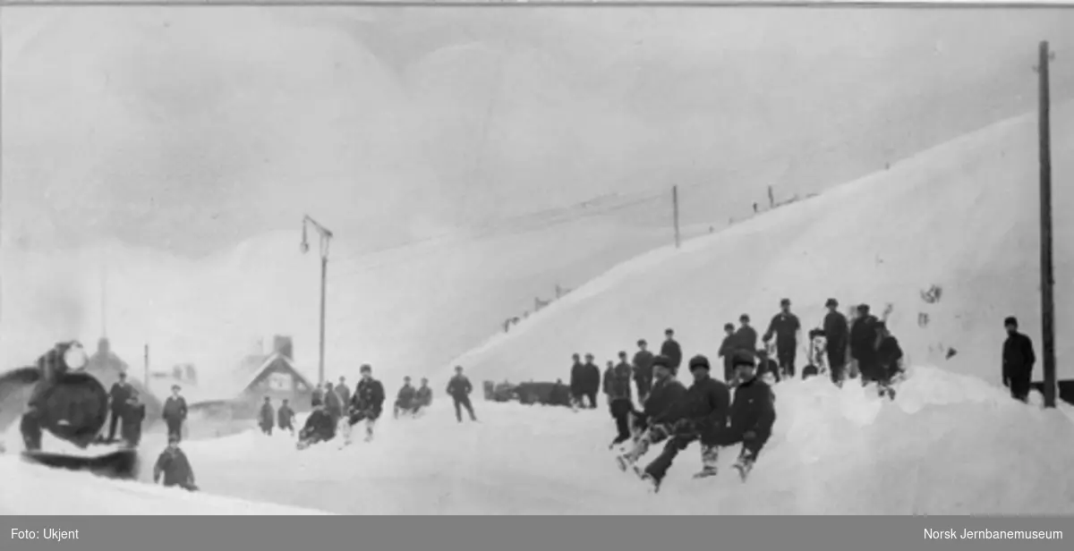 Vintermotiv fra Riksgrändsen stasjon med damplokomotiv og snømåkere