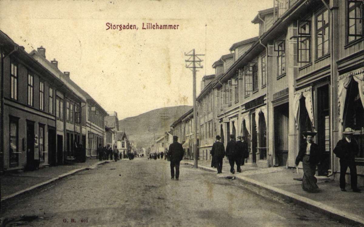 Postkort. Flere mennesker går i Storgaten i Lillehammer. Stemplet 12.09.1907.