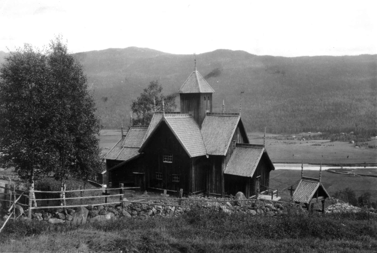 Uvdal kirke, Nore og Uvdal. 1930. Stavkirke. Kirkegård. Gravsteiner. Landskap med jorder, åser og fjell i bakgrunnen,
