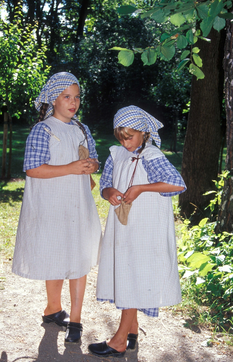 Levendegjøring på museum.
Ferieskolen 2003. To jenter venter på at skoletimen skal begynne.
Utenfor Skolestua, bygning nr. 196, Norsk Folkemuseum.