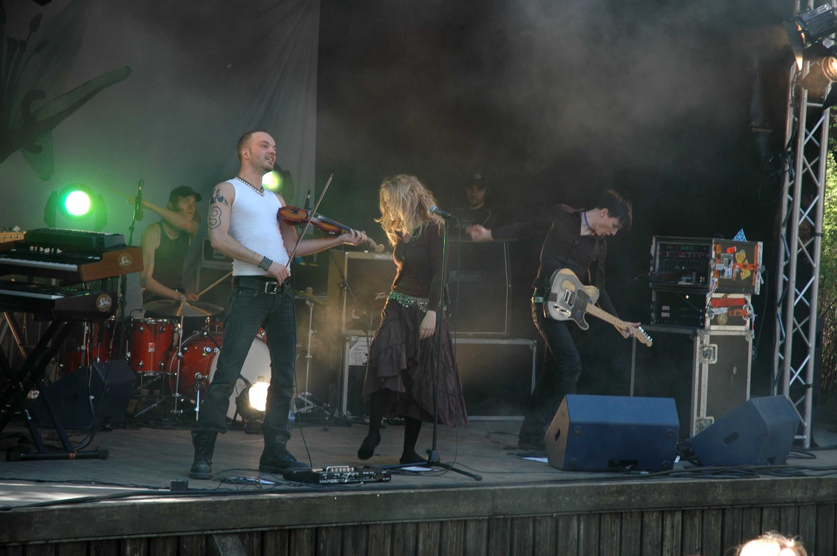 Musikkgruppen "Gåte", engasjert av Rikskonsertene, spiller for ca. 1000 ungdomsskole-elever per konsert, på friluftsteateret, nummer 349 på Norsk Folkemuseum  i mai 2005.