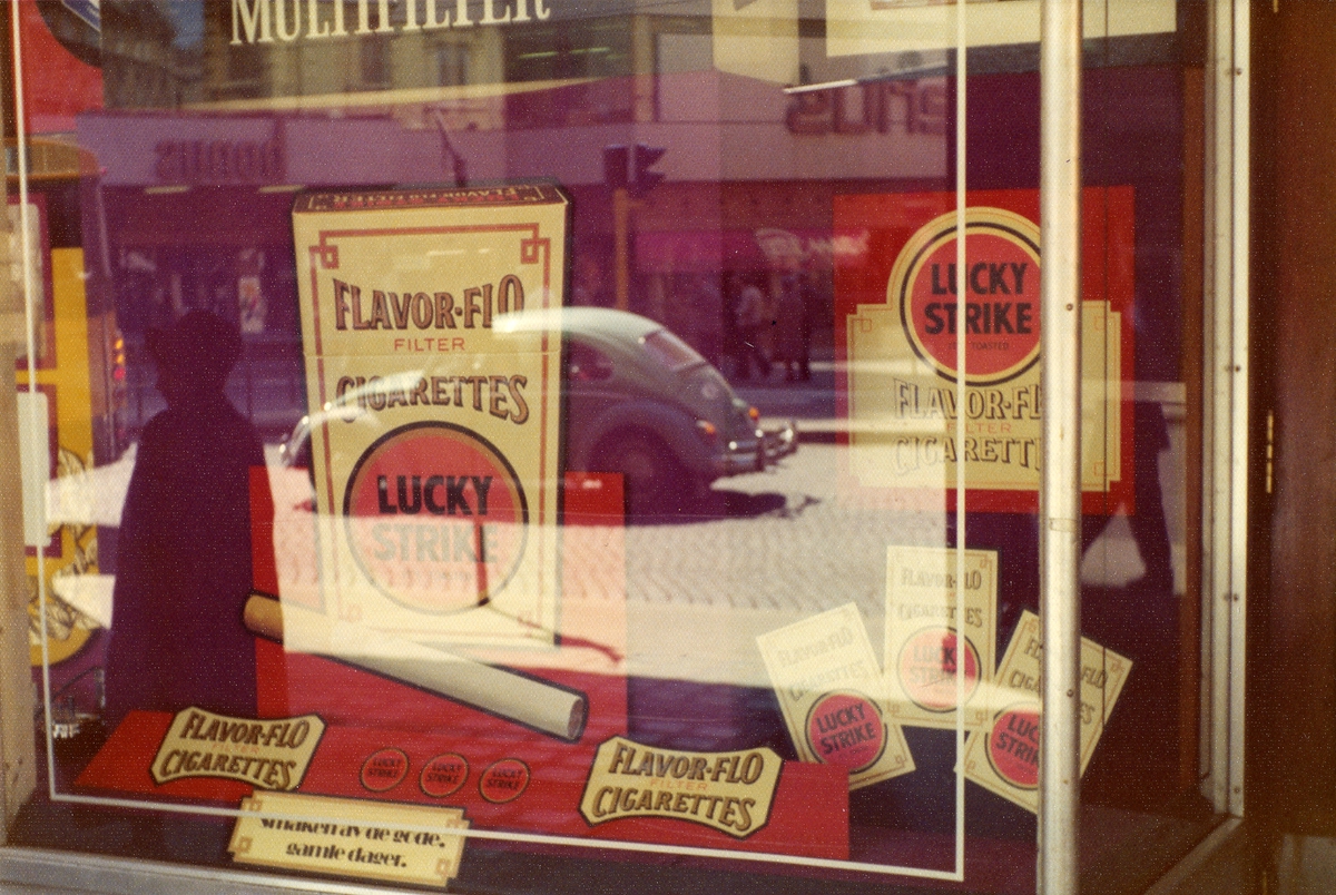 Vindusutstilling med reklame for Lucky Strike sigaretter hos tobakksbutikk på Storgata i Oslo.