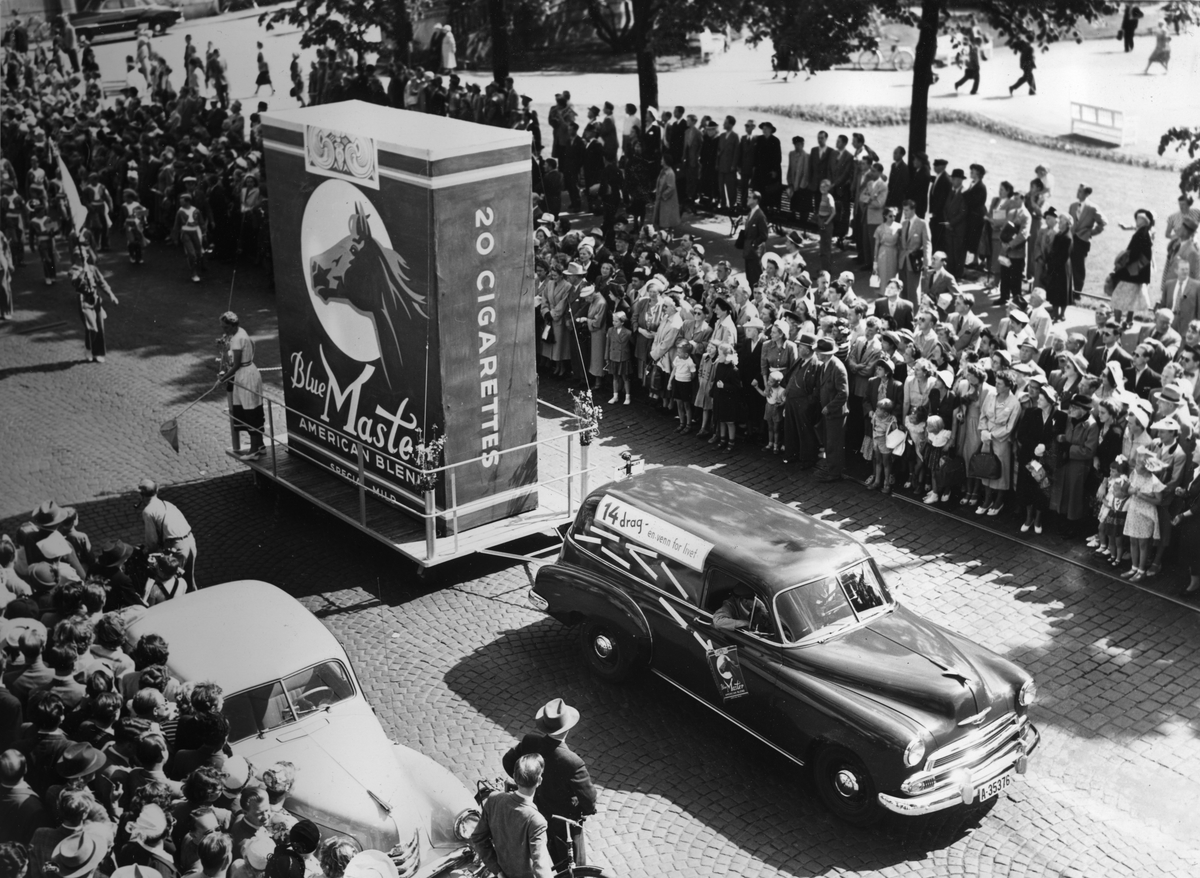 "Oslo-dagen" 14. juni 1952. Reklame for Blue Master sigaretter i et opptog med mennesker som har samlet seg rundt.