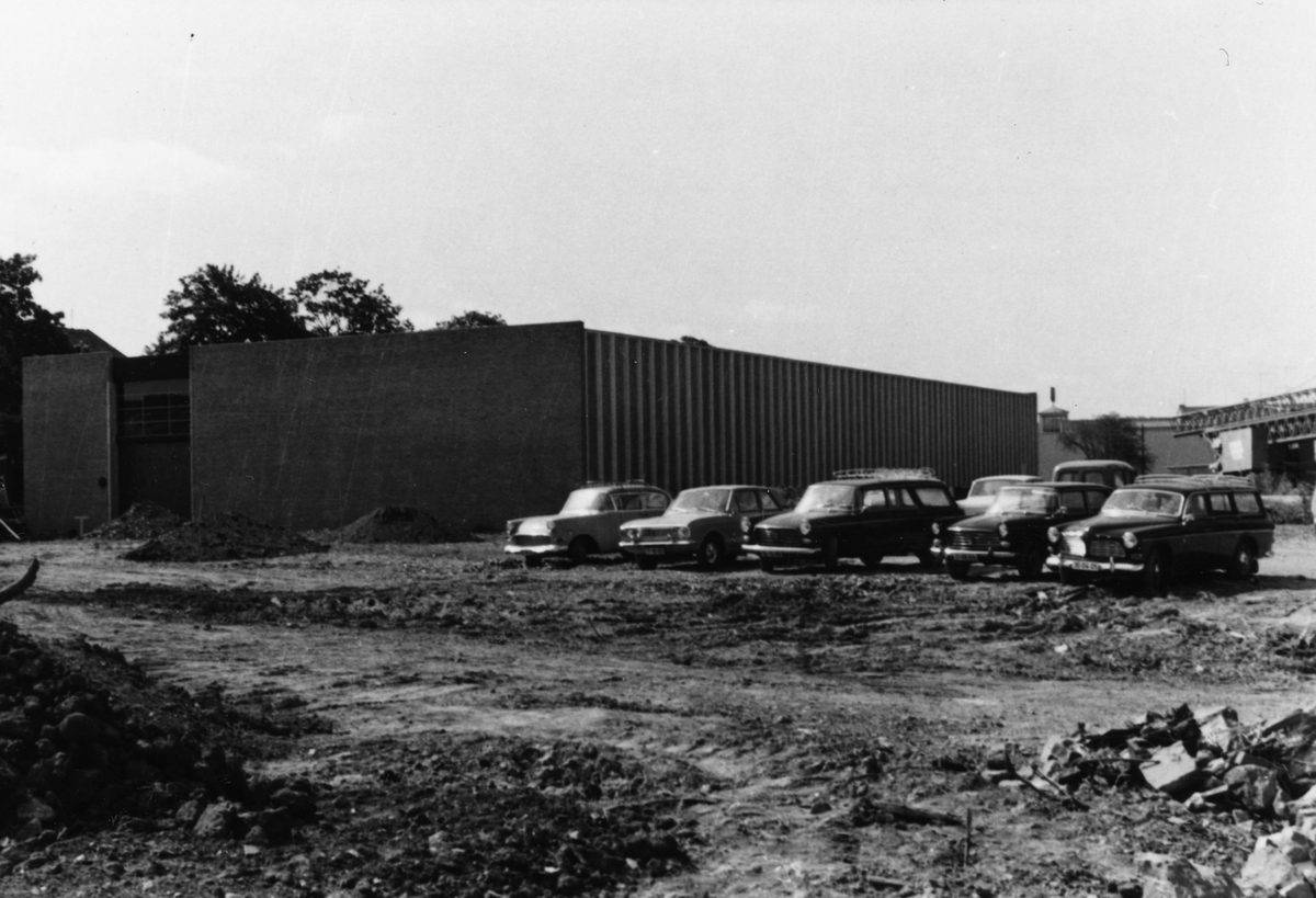 Byggeplass.
Konstruksjon av Tiedemanns Tobaksfabrik på Hovin i 1968. Parkerte biler ved siden av den nye fabrikken.
